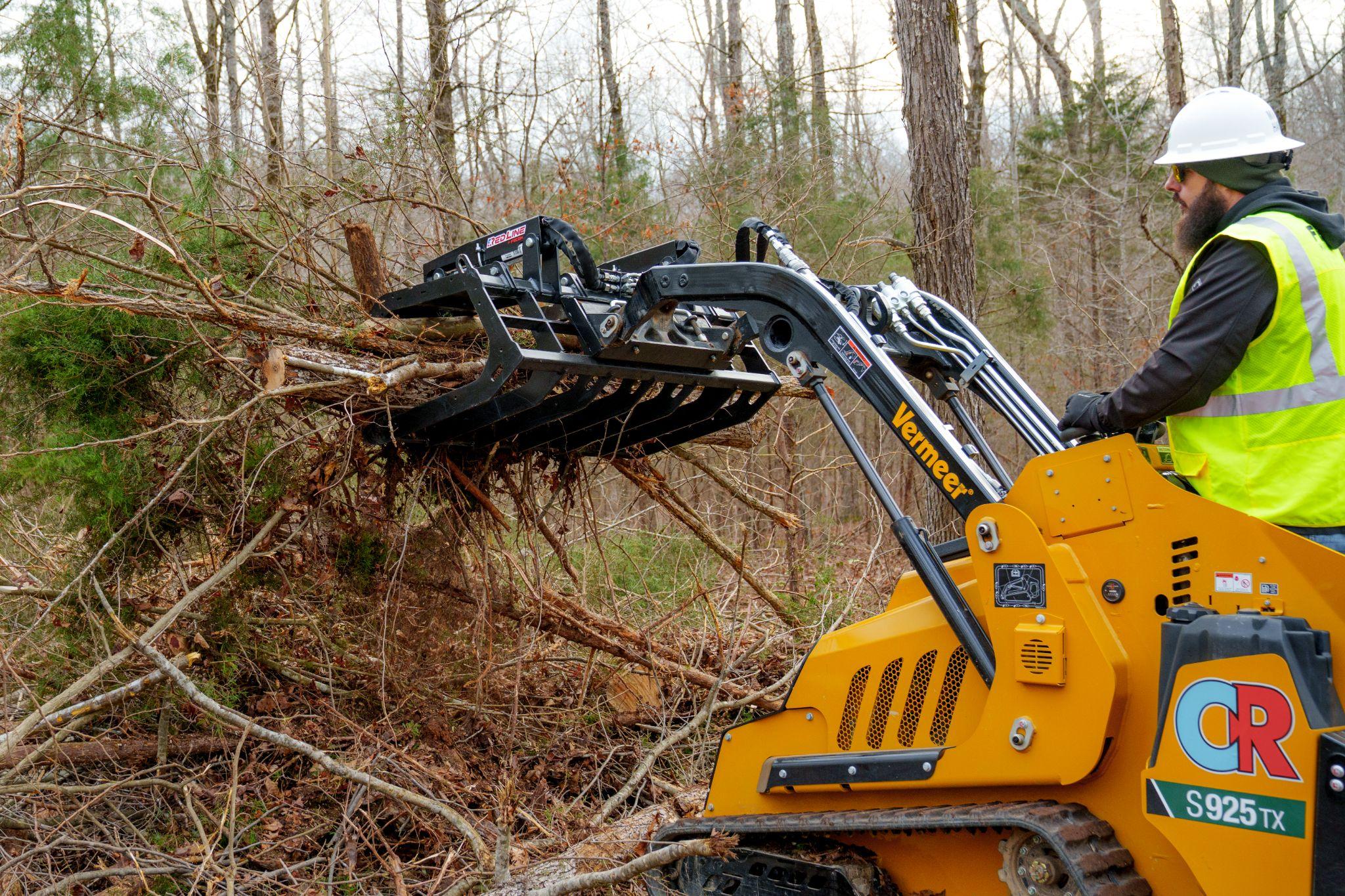 Operator using a Red Line brush grapple to clear downed brush